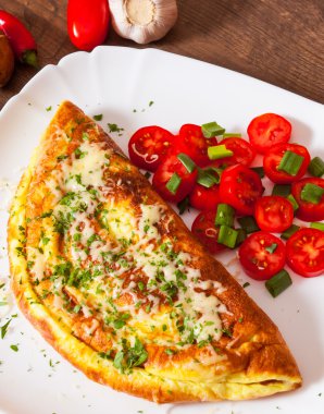 omlet peynir ve ahşap masa üzerinde bir tabak salata ile