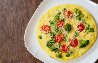 domates, brokoli ve bir plaka ahşap masa üzerinde beyaz peynir omlet