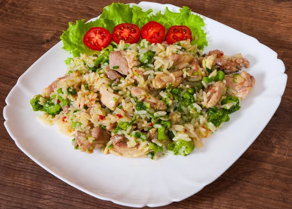 Hühnerfleisch mit Reis und Gemüse in einem Teller auf Holztisch — Stockfoto