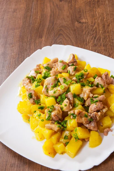 Stewed chicken meat with potatoes in a plate on wooden table — Stock Photo, Image