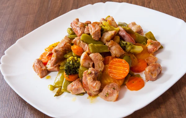 Gestoofde vlees met groenten in een plaat op houten tafel — Stockfoto