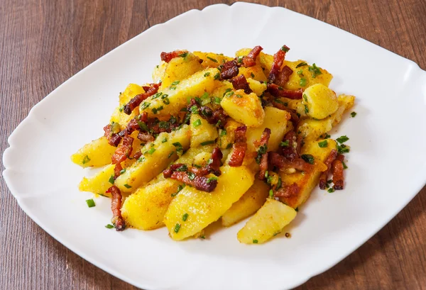 Batatas fritas com bacon em uma chapa na mesa de madeira — Fotografia de Stock