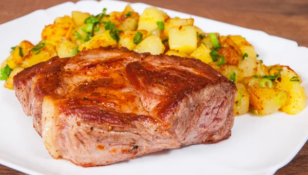 Grilled meat fillet steak with fried potato in a plate on wooden table — Stock Photo, Image