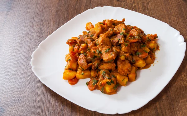 Viande cuite avec des légumes dans une assiette sur une table en bois — Photo