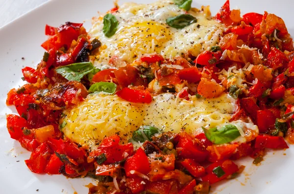 Fried eggs with vegetables and cheese in a plate on wooden table — Stock Photo, Image