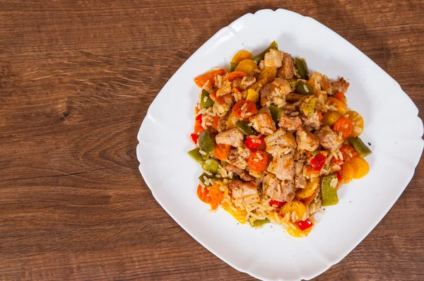 水稻与蔬菜和肉在一个木制的桌子上的盘子 — 图库照片