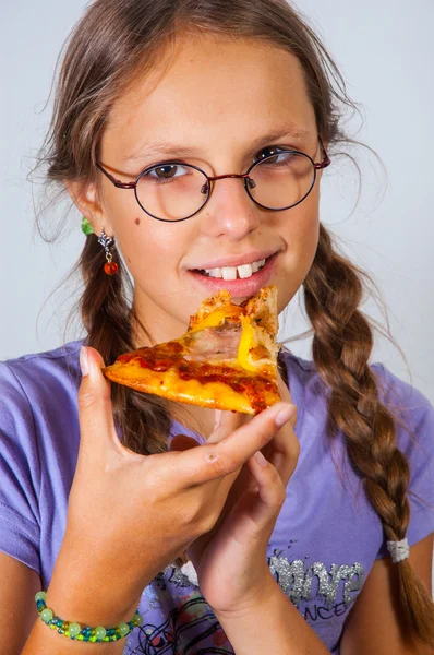 Young brunette girl eating a piece of pizza against a white background. — Stock Photo, Image