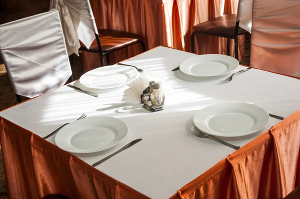Leerer weißer Teller in einer formellen Tischdekoration auf einem mit einer weißen Tischdecke gedeckten Tisch — Stockfoto