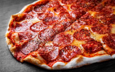 Mozzarella peynirli Pepperoni Pizza, salam, domates sosu, biber, baharat. İtalyan pizzası ahşap masa arkasında