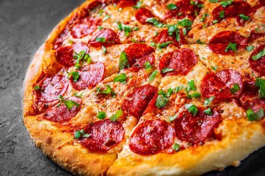 Mozzarella peynirli Pepperoni Pizza, salam, domates sosu, biber, baharat. Koyu gri arka planda İtalyan pizzası