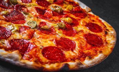 Mozzarella peynirli Pepperoni Pizza, salam, domates sosu, biber, baharat. Koyu gri arka planda İtalyan pizzası