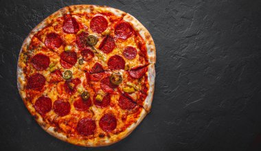 Mozzarella peynirli Pepperoni Pizza, salam, domates sosu, biber, baharat. Koyu gri arka planda İtalyan pizzası