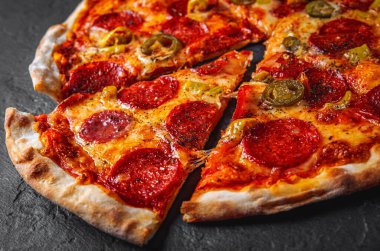 Mozzarella peynirli Pepperoni Pizza, salam, domates sosu, biber, baharat. Koyu gri arka planda İtalyan pizzası