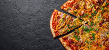 Mozzarella peynirli pizza, salam, domates sosu, biber, sosis, salatalık turşusu ve soğan. Koyu gri arka planda İtalyan pizzası