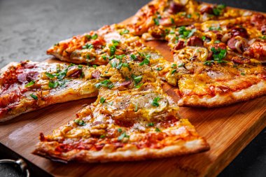 Mozzarella peynirli bir dilim pizza, salam, domates sosu, biber, sosis, salatalık turşusu ve soğan. Koyu gri arka planda İtalyan pizzası