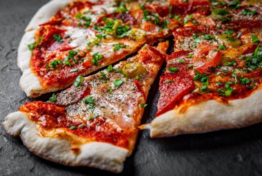 Mozzarella peynirli pizza, jambon, domates sosu, biber, salam. Koyu gri arka planda İtalyan pizzası