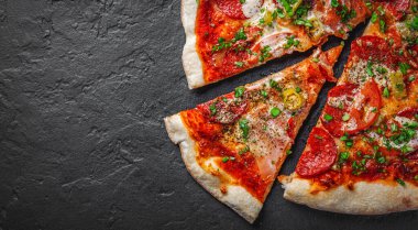 Mozzarella peynirli pizza, jambon, domates sosu, biber, salam. Koyu gri arka planda İtalyan pizzası