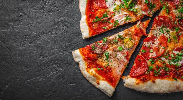 Mozzarella peynirli pizza, jambon, domates sosu, biber, salam. Koyu gri arka planda İtalyan pizzası