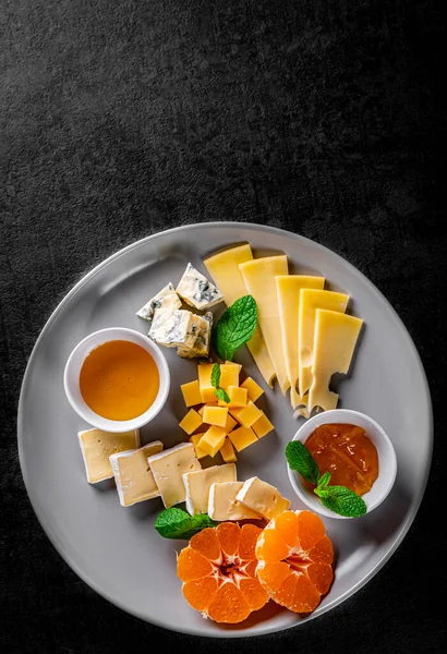 黒灰色のスレートの背景にチーズプレート — ストック写真