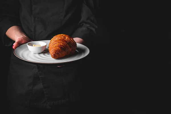 Chef Traje Negro Sostiene Sus Manos Plato Con Croissant Sobre —  Fotos de Stock