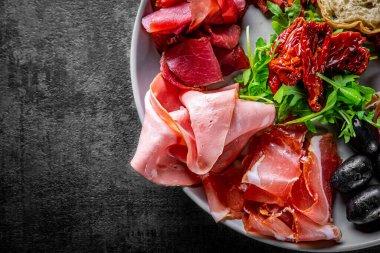 Et tabağı, salam, jambon, sırt, koyu gri arka planda prosciutto.