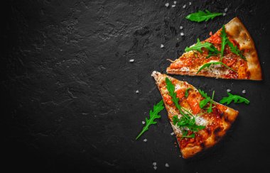 Mozzarella peynirli iki dilim pizza, somon balığı, domates sosu, roka. Koyu gri arka planda İtalyan pizzası