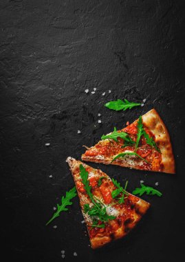 Mozzarella peynirli iki dilim pizza, somon balığı, domates sosu, roka. Koyu gri arka planda İtalyan pizzası