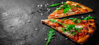 Mozzarella peynirli iki dilim pizza, somon balığı, domates sosu, roka. Koyu gri arka planda İtalyan pizzası