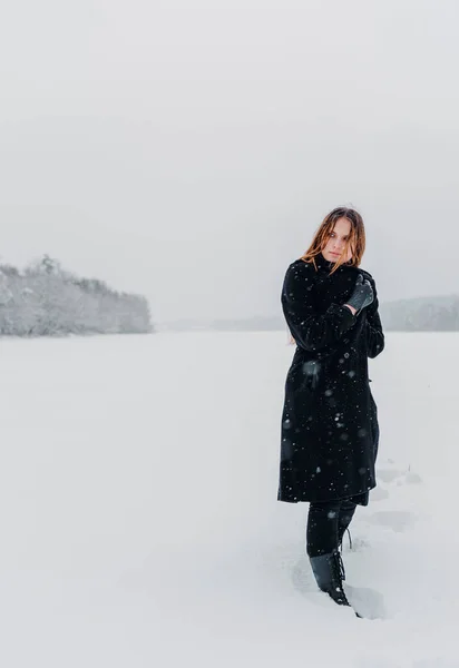 年轻少女的肖像 长发黑衣 田里的自然雪原背景 冬季户外照片 — 图库照片
