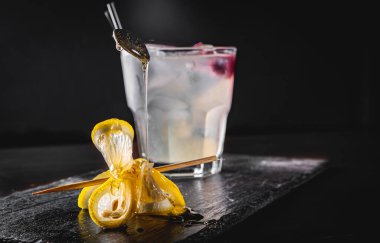 Limonlu cin kokteyli ve siyah arkaplanda bal