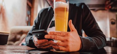 Erkek eli kamerayı kapat, akıllı telefonu tut, bira iç ve barda veya barda mesaj oku.