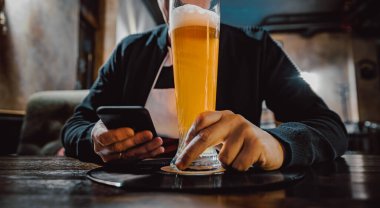 Erkek eli kamerayı kapat, akıllı telefonu tut, bira iç ve barda veya barda mesaj oku.