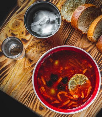 Solyanka çorbası et, sosis, sebze, zeytin ve limon kasede siyah ahşap masa arkasında.