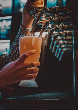 Bira musluğundaki barmen bir restoranda ya da barda servis edilen bardakta bira dolduruyor.
