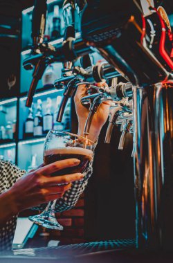 Bira musluğundaki barmen bir restoranda ya da barda servis edilen bardakta bira dolduruyor.