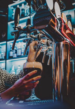 Bira musluğundaki barmen bir restoranda ya da barda servis edilen bardakta bira dolduruyor.
