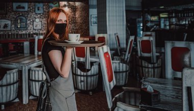 Kafede duran genç garsonun portresi. Garsonun elinde bir tepsi dolusu çatal bıçak tutan kız. Restoran servisi.