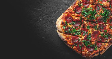 Mozzarella peynirli Pepperoni Pizza, salam, domates sosu, biber, baharat. Koyu gri arka planda İtalyan pizzası
