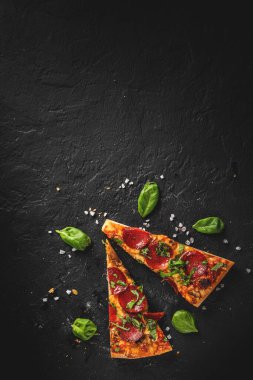  Mozzarella peynirli, salamlı, domates soslu, biberli, baharatlı iki dilim Pepperoni pizza. Koyu gri arka planda İtalyan pizzası