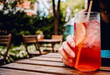 Kadın bardakla limonata kokteyli açık kafedeki masada.