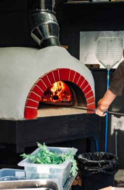 Şef pizza alır. İtalyan pizzası odun ateşinde pişirilir.