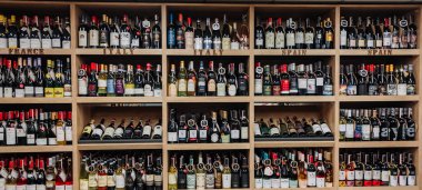 Minsk, Belarus - 3 Temmuz 2021: Bir süpermarketin ahşap rafında çeşitli şarap şişeleri satışı.