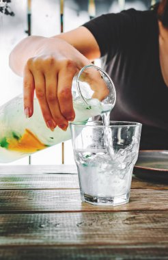 Kadın eli limonata ya da mojito kokteyli limon, portakal ve kırsal mavi arka planda buzlu nane.