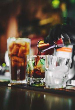 Siyah eldivenli bir barmenin elleri tezgahta kokteyl yapıyor..