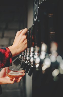 Kadının eli bardağı tutuyor ve musluktan hafif bira döküyor. tapot odası