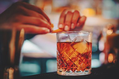 Kadın barmen eli negroni kokteyli yapıyor. Negroni klasik kokteyli ve tatlı vermut ve kırmızı acı likörlü cin kısa içeceği.