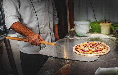 Mutfakta pizza yapan şef fırıncının eli. İniş küreğini tak ve fırına gönder..
