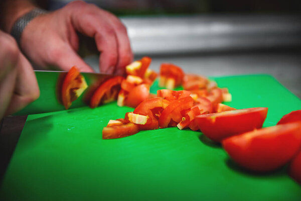 Chef hand slicing fresh ripe tomatoes on a chopping board