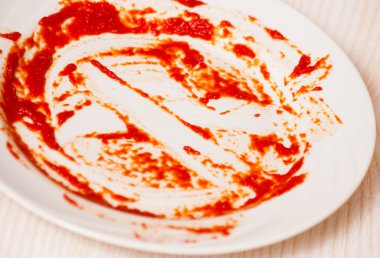 Kirli tabak masaya. Bir tabağa bulaşmış domates sosu.