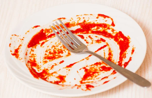 Placa sucia sobre la mesa. Salsa de tomate untada en un plato . — Foto de Stock